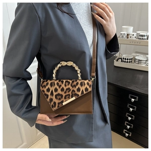 Close-up of leopard print flap and golden twisted handle on a retro brown bag