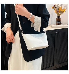 Détail du sac seau en cuir grainé blanc avec des finitions métalliques dorées élégantes