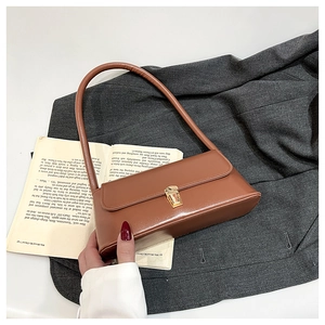 Detail of vintage brown faux leather underarm bag with gold metal buckle and shoulder strap