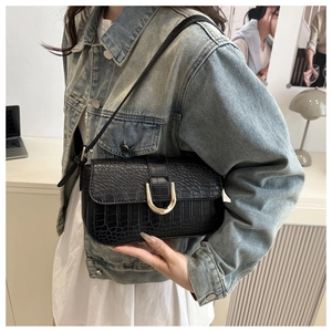 Detail of black crocodile texture handbag with golden U-shaped buckle on minimalist flap