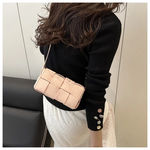 Detail of light pink crossbody bag with wide woven leather straps and snakeskin texture