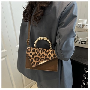 Detail of a leopard print crossbody bag with gold twisted handle and leather stitching
