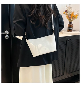 Détail du sac seau en cuir grainé blanc avec finitions dorées porté par un mannequin