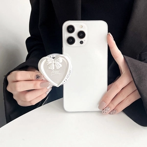 Close-up of white heart phone grip with bow decoration held against a black suit