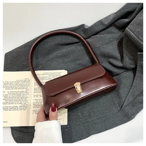 Detail of vintage burgundy leather baguette bag with gold buckle on grey blazer