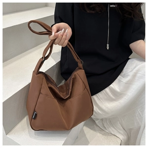 Close-up of a brown nylon hobo bag with wide shoulder strap and brand label detail