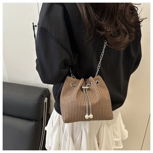 Detail einer braunen geflochtenen Eimertasche mit Perlen-Kordelzug und silberner Kette