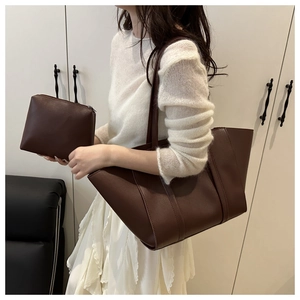 Deep coffee large tote bag and matching pouch shown on a model in a minimalist setting