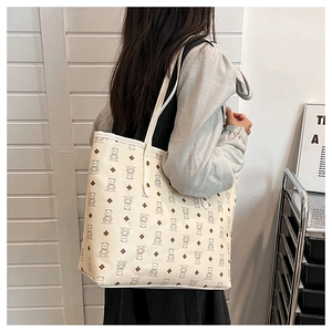 Detail of the tote bag showing bear monogram print and metallic stud fastener details