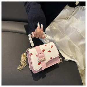 Detail of pink and white cherry print handbag with pearl handle and golden chain