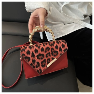 Close-up of leopard print handbag featuring a red leather flap and gold snake-twist handle