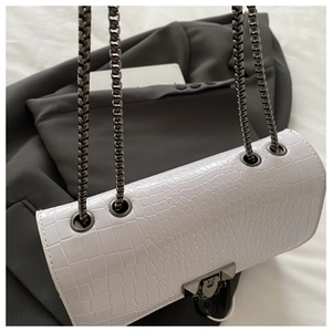 Close-up of white croc-embossed leather texture with stylish V-shaped metal buckle detail