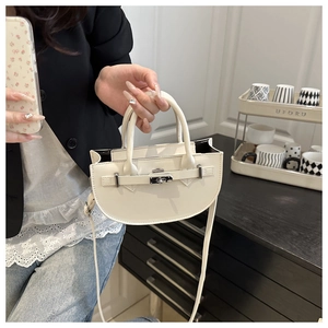 Vue détaillée d'un sac bandoulière demi-lune blanc crème avec boucle décorative en cuir