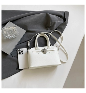 Detailansicht der weißen Handtasche aus Narbenleder mit silbernem Drehschloss und feinen Nähten