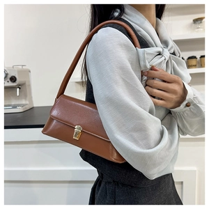 Close-up of retro brown leather baguette bag with gold buckle on a stylish model