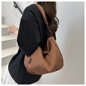 Detail showing the brown nylon crescent bag with brand label and spacious interior