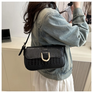 Detail of black crocodile texture bag with elegant gold horseshoe metal buckle closure