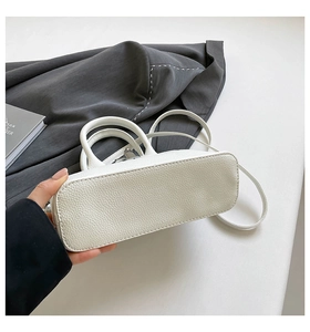 Nahaufnahme der weißen Handtasche aus Leder mit Fokus auf Bodennaht und Doppelgriffen