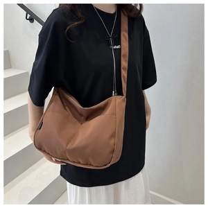 Brown canvas crossbody tote bag worn by model on stairs, minimalist casual style