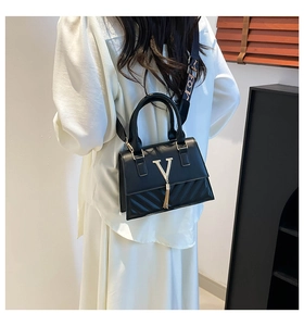 Detail of black quilted leather handbag with gold V logo, tassel and wide strap
