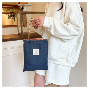 Détail du sac cabas en jean avec poignées tissées colorées et doublure vintage à carreaux