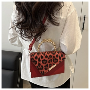 Close-up of leopard print crossbody bag with red body and golden twisted chain handle