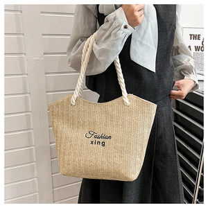 Detail of hand-woven straw tote with black fashion embroidery and cotton rope handles