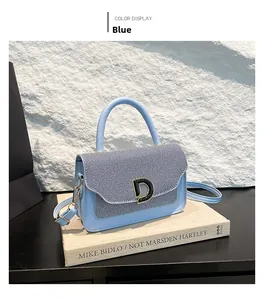 Dettaglio della borsa in pelle blu con patta in tessuto a contrasto e fibbia a D in metallo