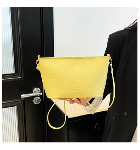 Détail du sac seau en cuir jaune grainé avec bandoulière et finitions métalliques dorées