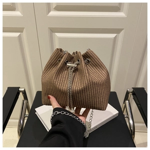 Détail d'un sac seau tissé marron avec cordons ornés de perles et bandoulière chaîne