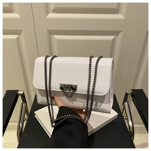 Detail of white crocodile pattern shoulder bag with dark grey metal buckle and chain strap