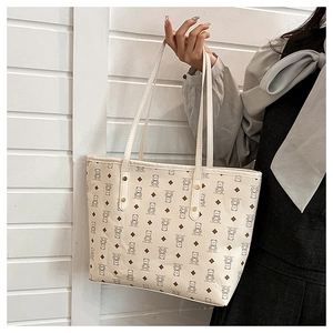 Detail of cream tote bag with bear pattern, PU leather texture and metal rivet accents