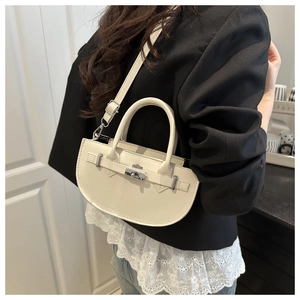 Modèle portant un sac à bandoulière demi-lune blanc cassé en cuir texturé fin