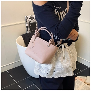 Detail of light pink PU leather handbag with knot handle and smiley charm on model