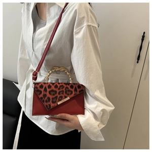 Detail of red crossbody bag with leopard print flap and spiral texture metal handle
