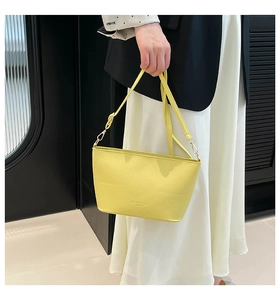 Gros plan d'un sac seau jaune clair en cuir texturé avec logo gaufré élégant