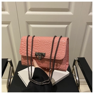 Detailed close-up of pink crocodile pattern patent leather handbag with dark metal buckle