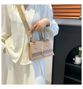Detail of beige crossbody bag with quilted pattern and gold V-shaped buckle clasp
