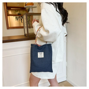 Détail du sac cabas en denim bleu foncé avec poignées tressées et doublure à carreaux