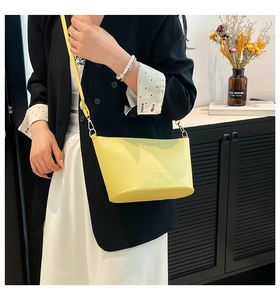 Détail d'un sac seau jaune en cuir grainé assorti à un blazer noir élégant pour femme