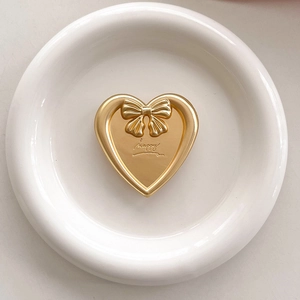 Detail of a matte gold heart phone grip with a bow accent and happy engraving