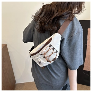 Vue détaillée du sac bandoulière crème avec cordons marrons et écusson logo mode