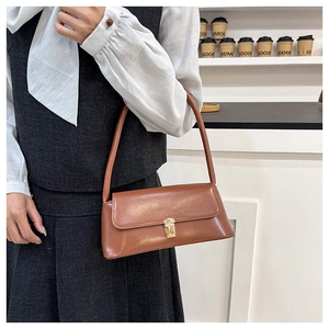 Detailed view of brown leather underarm bag with elegant gold metal square push lock