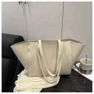 Détail du sac cabas blanc crème avec logo FASHION sur une table en bois noir