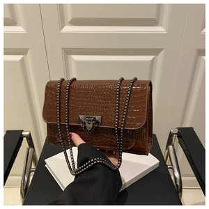 Detail of brown crocodile pattern shoulder bag with silver rivet turn-lock and chain strap