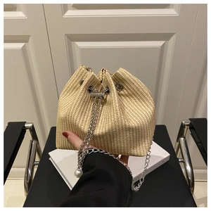 Détails de la texture du sac seau en paille tressée beige avec chaîne et perle