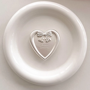 Detail of silver heart phone socket with bow and happy engraving on white plate
