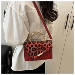 Detail of red leather crossbody bag with leopard print flap and golden snake-textured handle