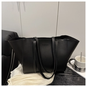 Détail d'un grand sac cabas en cuir noir avec texte embossé et plis sur les côtés