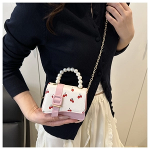Detailed shot of white cherry print mini bag with pink flap and pearl handle